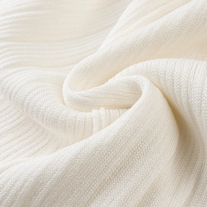 Macro shot of cream knit ribbed fabric showing soft vertical texture and material detail