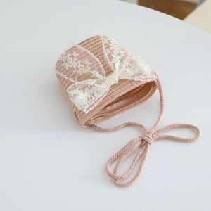Detailed view of pink straw crossbody bag with large white lace bow for girls