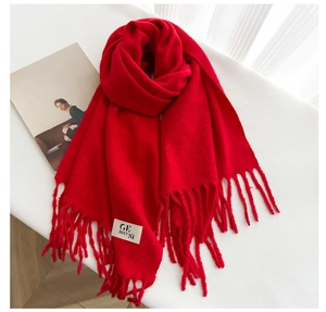 Detail of soft red cashmere-like scarf with textured tassel fringe and minimal white label