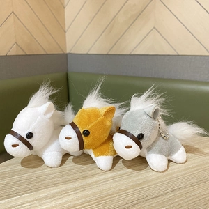 Drie kleurrijke pluchen pony sleutelhangers in wit, geel en grijs met pluizige manen