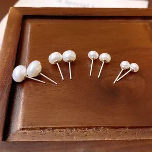 Minimalist silver freshwater pearl earrings set in various sizes on a wood tray