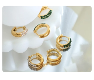 Detail of 18K gold-plated huggie earrings with white zircons and green gemstones