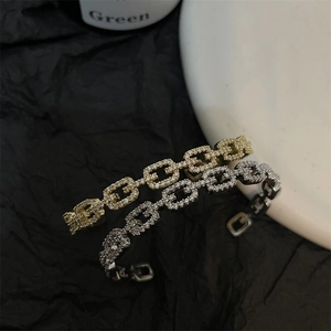 Macro shot of gold and silver chain-link open bangles set with sparkling pavé zircons
