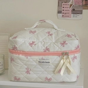 Quilted makeup bag with pink bow pattern and dual zipper closure for travel