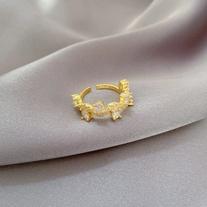 Detail of adjustable gold ring with branch design and row of sparkling zircon stones