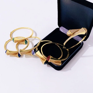Detail of gold geometric tower bangles with colorful gemstones and micro-pave crystals