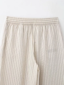 Detailed close-up of elastic waistband on beige striped trousers with fine stitching