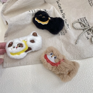 Close-up of cute plush pins featuring cat and panda embroidery on beige linen cloth