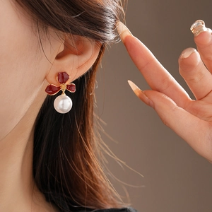 Detail view of Ancora red flower earrings with pearls on a model showing vintage French style