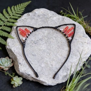 Close-up of cat ear headband with red crystals and beads on a natural rock background