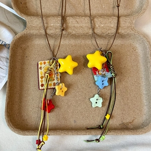 Star-shaped acrylic pendant necklace with colorful charms and woven cord on paper tray