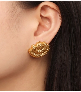 Macro shot of 18K gold plated fan-shaped earrings with hammered texture on a model's ear