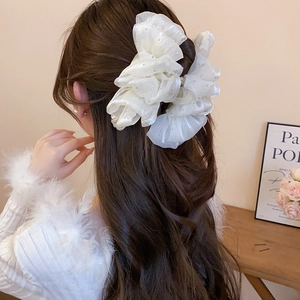 Detail of white mesh bow hair claw with silver sparkles on long hair styling
