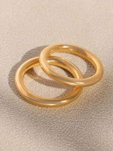 Close-up of dual gold plated titanium rings with zircon inlay on grey leather background