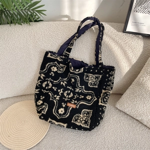 Detail of vintage plush tote bag with geometric patterns and leather logo on sofa