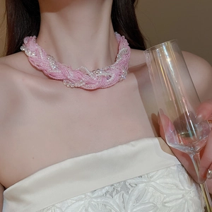 Detailed view of layered pink pearl choker with lace bow and champagne glass background