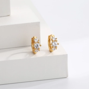 Macro shot of gold-plated silver hoop earrings featuring triple cubic zirconia stones