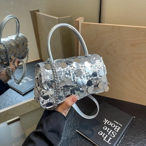 Detail of silver sequin handbag with round metallic discs and a rigid curved top handle
