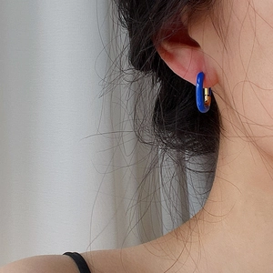 Minimalist U-shaped gold earrings with bright blue enamel on female model ear
