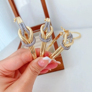 Verstellbare goldene Knotenarmreifen mit glitzernden Kristallen auf einer Schmuckschatulle