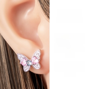 Macro shot of butterfly ear stud with pink and blue stones on model's ear