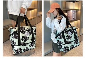 Detail of mint green elephant print travel bag showing handheld and shoulder carry styles