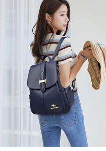 Detail of dark blue faux leather backpack showing pebbled texture and gold kangaroo logo