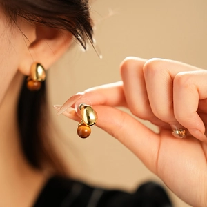 Close-up of vintage faux tiger eye drop earrings with gold metal accents on model