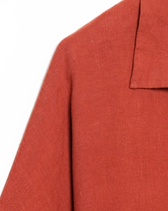 Détail du col d'une robe en lin rouge rouille montrant la texture naturelle du tissu