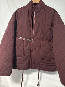 Close-up of deep wine red quilted jacket featuring a stand collar and symmetrical pockets