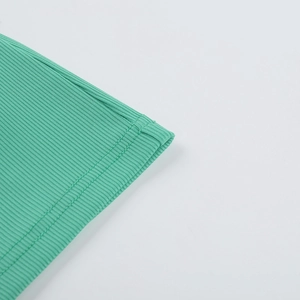 Detailed macro view of the green ribbed knit fabric texture and high-quality edge stitching