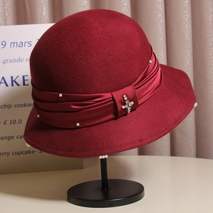 Detail of burgundy wool fedora with satin bow, white pearls, and rhinestone embellishment