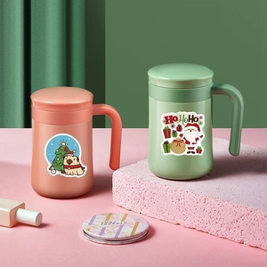 Close-up of pink and mint green Christmas mugs decorated with festive cartoon stickers