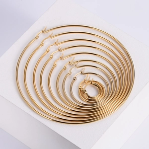 Set of 9 pairs golden stainless steel hoop earrings in various sizes on stone base