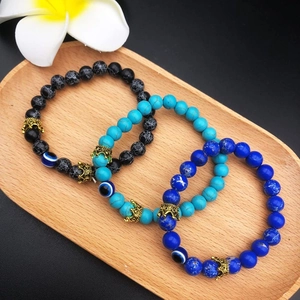 Three-piece turquoise and evil eye beaded bracelets with gold crown charms on wood tray