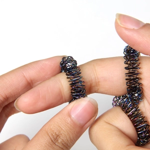 Close-up of a person using a colorful metal spring ring for finger massage and stress relief