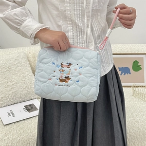 Close-up of quilted light blue makeup bag with cute dog embroidery and pink lanyard