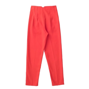 Detail of bright red high-waisted trousers with V-cut waist and central crease design