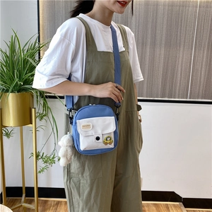 Détail du petit sac bandoulière en toile bleu marine avec pendentif en peluche blanc