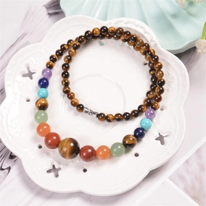 Close-up of colorful tiger eye and chakra beads on a white porcelain dish