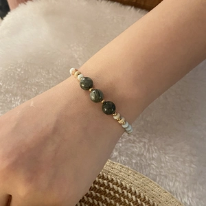 Retro natural stone beaded bracelet with dark green gems and gold accents on wrist