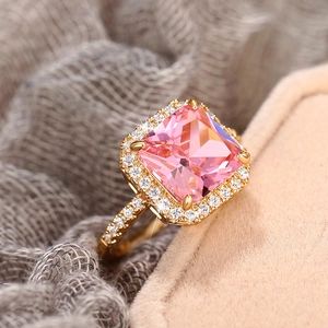 Macro shot of gold square ring with pink gemstone and diamonds on jewelry box