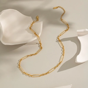 Artistic top view of gold paperclip link chain bracelet on textured grey stone surface