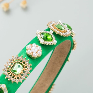 Macro detail of Baroque headband with emerald gems, pearls and golden filigree
