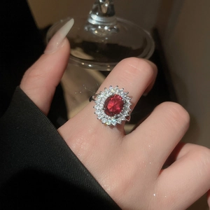 Gros plan d'une bague style rubis ovale avec double halo de zircons sur la main