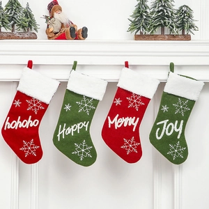 Set of 4 red and green plush Christmas stockings with festive embroidery hanging on mantle