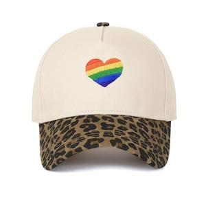 Dettaglio del ricamo cuore arcobaleno su corona beige e visiera con stampa leopardata