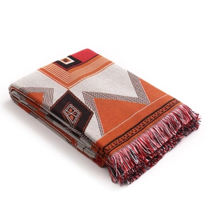 Close-up of geometric knit blanket with orange patterns and woven fringe details