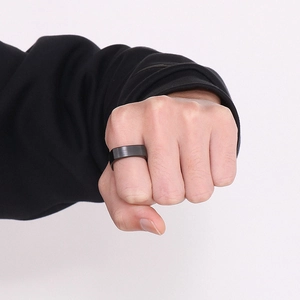 Close-up of matte black stainless steel square ring on a male hand against white background