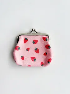 Close-up of pink glitter coin purse featuring strawberry print and metal kiss-lock closure